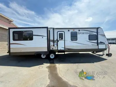 The Sportsmen S330IK travel trailer by KZ features triple slides and a kitchen island. As you enter...