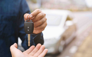 Vendeur particulier remettant les clés de sa voiture à l'acheteur. 