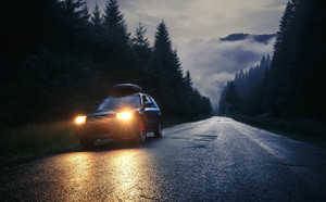 SUV driving at night in the forest with headlights on