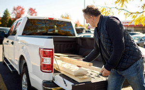 Man unloading wood from the bed of his pickup truck