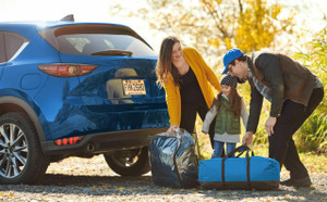 A family with a young child taking camping equipment from their car