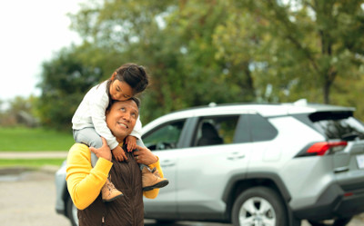 Father and daughter walking out of their car, a grey Family SUV