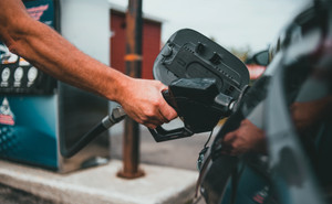 Close up of driver pumping gas at gas station - post pandemic car shopping and gas price hacks 