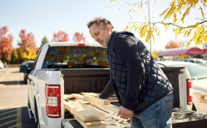 Man unloading wood from the bed of his pickup truck