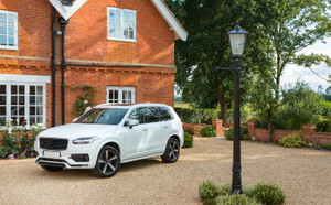 7 seat suv white car in front of red brick-house 