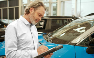 Man looking at clipboard in a car dealership