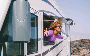 Vue de l'extérieur d'un van, femme profitant de la vie par les fenêtres ouvertes 