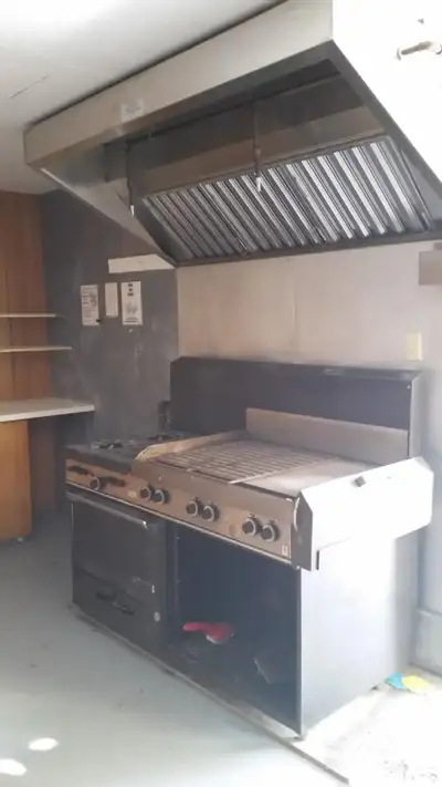 Commercial Garland Grill with four burners and oven, also comes with canopy exhaust hood. In good wo...