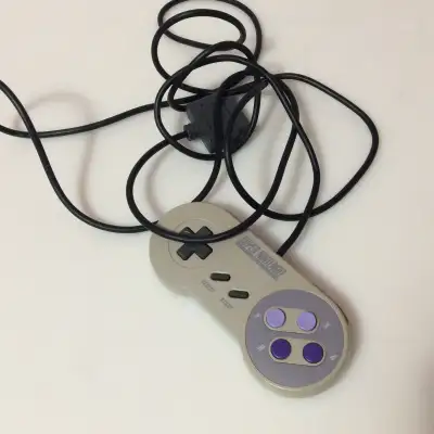 This is an original Super Nintendo Entertainment System (SNES) controller, specifically the North Am...