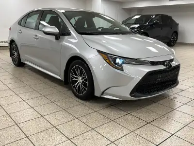 Dawn paints the streets in quiet silver as the 2021 Toyota Corolla L slips from the curb, its LED be...