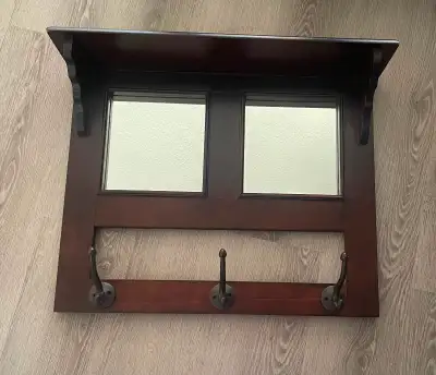 Wooden wall mirror with cast iron hooks for entryway. Measurements are 19.5” high and 23.5” wide.