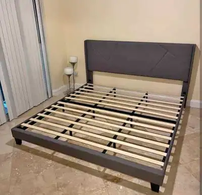 This queen size bed frame is designed with a modern aesthetic, featuring a sleek grey fabric and a g...