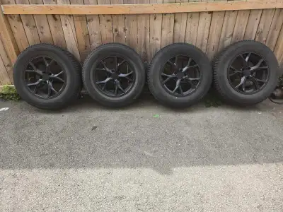 These used winter tires are mounted on custom black rims, providing excellent traction and a sleek a...