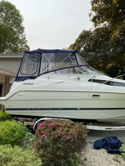 Spacious Bayliner Ciera 2355 cabin cruiser. Boat has white hull and blue canvas enclosure. Interior...