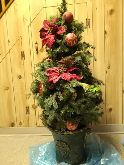 Potted artificial Christmas tree with decorations., View more