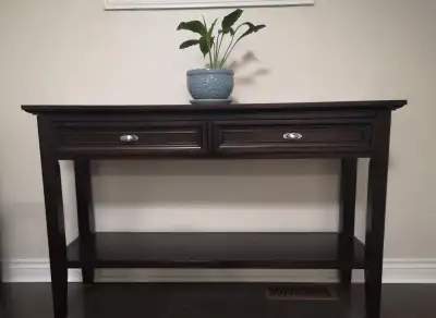 This elegant dark wood console table features two spacious storage drawers and a lower display shelf...