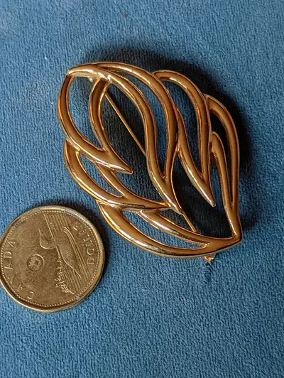 Large goldtone brooch in a filigree shape, looks like a flame to some people, but to others its a le...