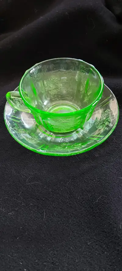 Green depression glass cup and saucer. No chips. Photos show flaws in glass, seam and glows green un...