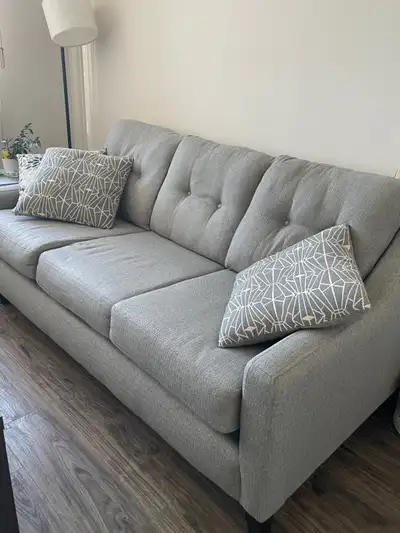 Grey sofa with accent cushions, seats three., View more
