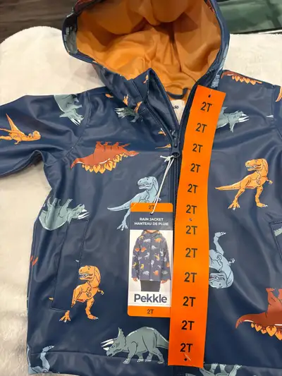 This brand new Pekkle dinosaur print rain jacket for boys, size 2T, is perfect for keeping your litt...