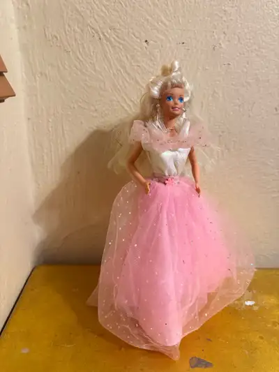 This is a used Barbie doll with fiber optics. She has blonde hair and is wearing a pink gown. The do...