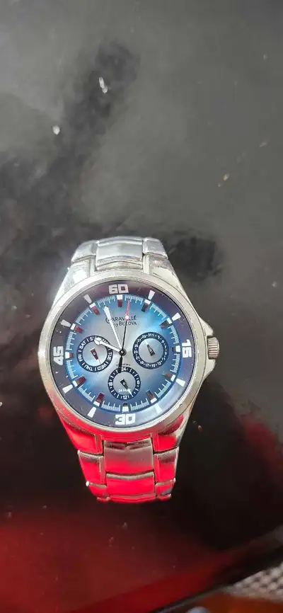 This is a used Caravelle by Bulova men's watch, featuring a stainless steel band and a stylish blue...
