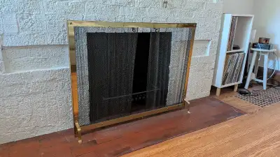 This is a used, decorative fireplace screen with a brass frame and mesh insert, perfect for adding a...