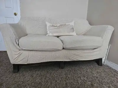 Comfortable loveseat with a white leaf-patterned cover, and cousion for adding a cozy touch to any l...