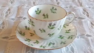 FINE BONE CHINA CUP AND SAUCER - WHITE SWIRL WITH PURPLE THISTLES. MADE IN ENGLAND. NUMBERED. IN VER...