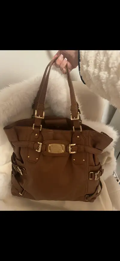 Ce sac à main Michael Kors en cuir marron est un accessoire de mode élégant et pratique. Ce sac a ét...