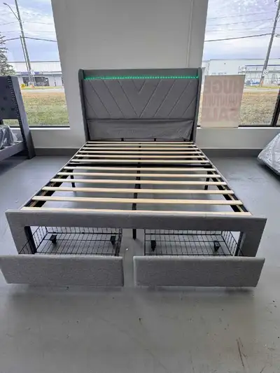 This queen bed frame features a modern design with a grey fabric finish and an integrated LED light...
