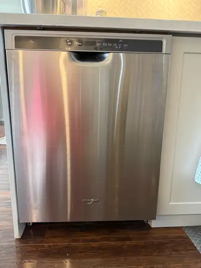 Stainless steel Whirlpool dishwasher has front control panel and recessed handle. Interior is clean...