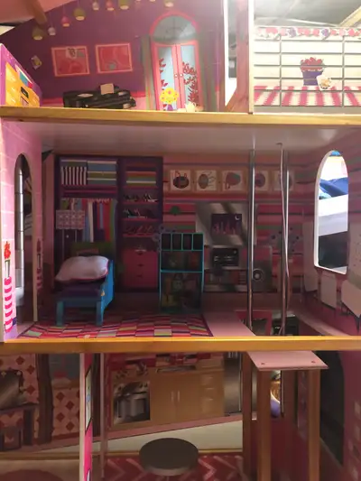 A doll house with a elevator and some doll furniture large doll house plus some Barbie dolls I only...