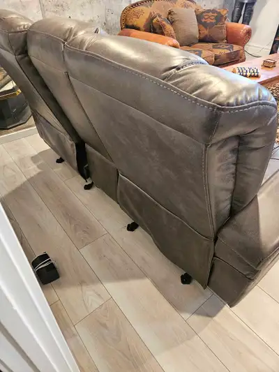 Ce fauteuil inclinable double en cuir marron présente des coutures en losange et des porte-gobelets...