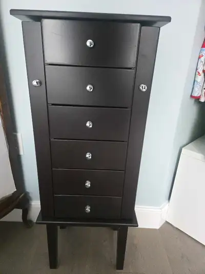 This jewellery box cabinet features five drawers and a top compartment with a mirror, perfect for or...