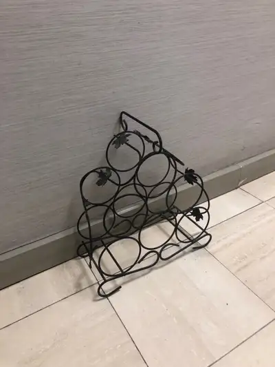 Ornate metal wine rack. Holds six bottles. Features decorative leaf accents. Black finish. Freestand...