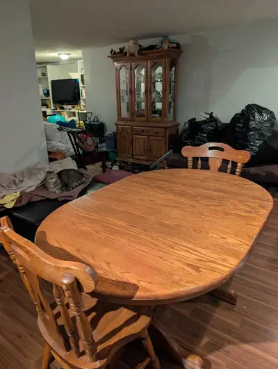 This pre-owned solid oak dining set features a sturdy oval table paired with matching chairs and a d...