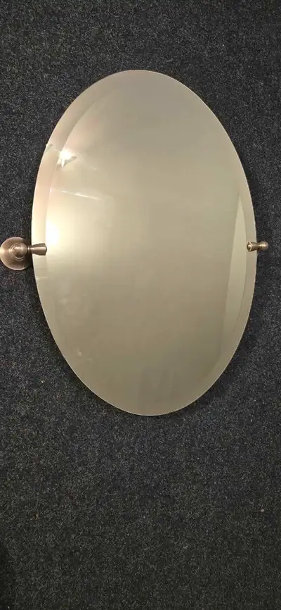 Bathroom mirror with mounting brackets. Oval shaped and bevil sides. Mirror dimensions are 19 wide b...