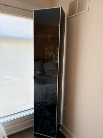 Stylish tall cabinet. Black wood grain finish. Frosted glass door has pretty floral design. Multiple...