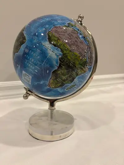 This elegant world globe features a detailed map with vibrant blue oceans and contrasting landmasses...