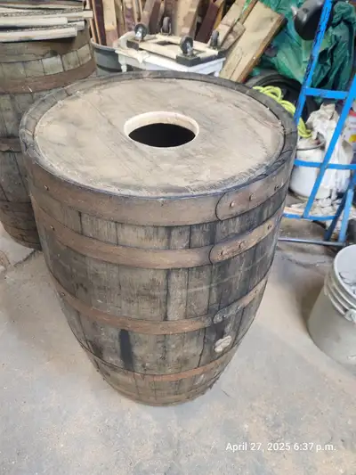 Oak rain barrels made from retired whiskey barrels - rings are secured and we cut a 6" hole in the m...