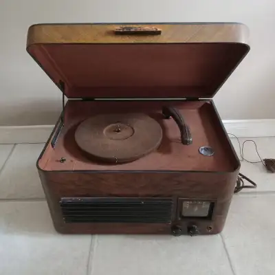 Model V-100 Tube Radio/Record Player. It combines a tube radio and a record player in a wooden cabin...