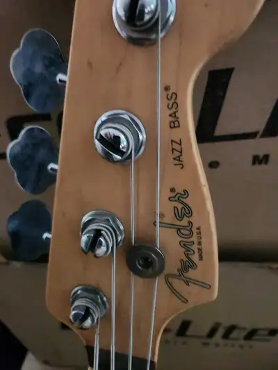 This is a used Fender Jazz Bass guitar with a sleek black finish and a white pickguard, delivering t...