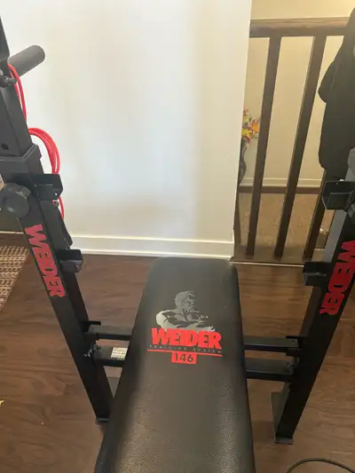 Weider 146 Bench for sale with about 100lbs in weights and 1inch diameter barbell. Used condition, f...