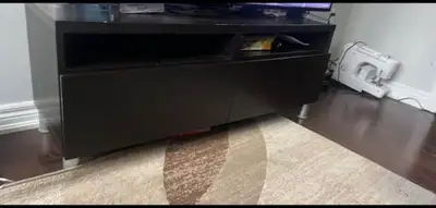 Dark brown media console. Has open shelves and two closed cabinets for storage. Silver legs.have som...