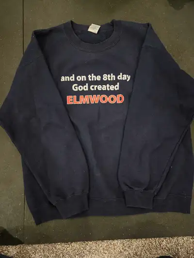 This is a navy blue "and on the 8th day God created Elmwood" sweater, perfect for anyone who loves t...