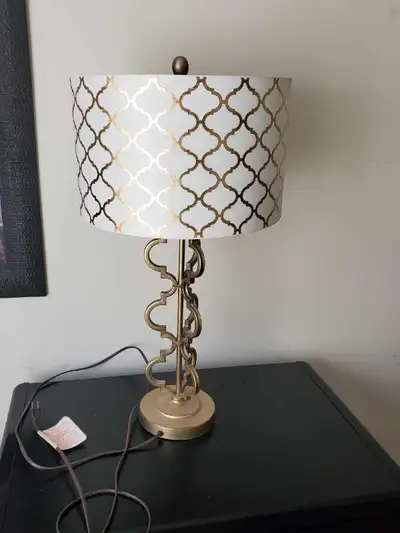 Add a touch of elegance to your space with this stylish table lamp, featuring a white and gold patte...