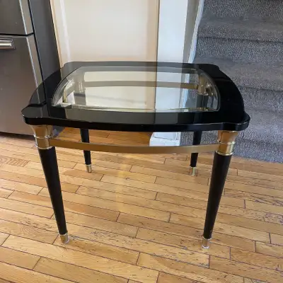 This chic, small coffee or side table features a sleek black and gold design with a glass top, perfe...