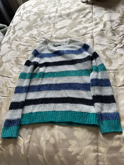 Women's long-sleeved sweater. Features horizontal stripes in teal, grey, black and blue. Crew neck.