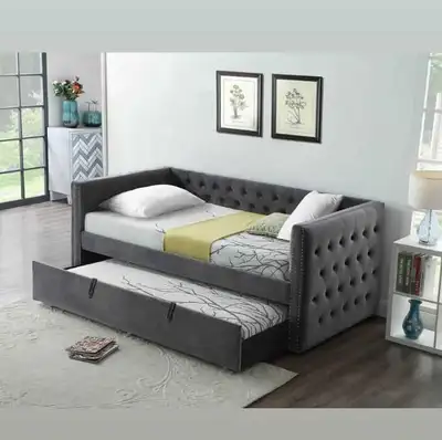 This is a twin-size daybed with a trundle, featuring a stylish grey button-tufted design, perfect fo...